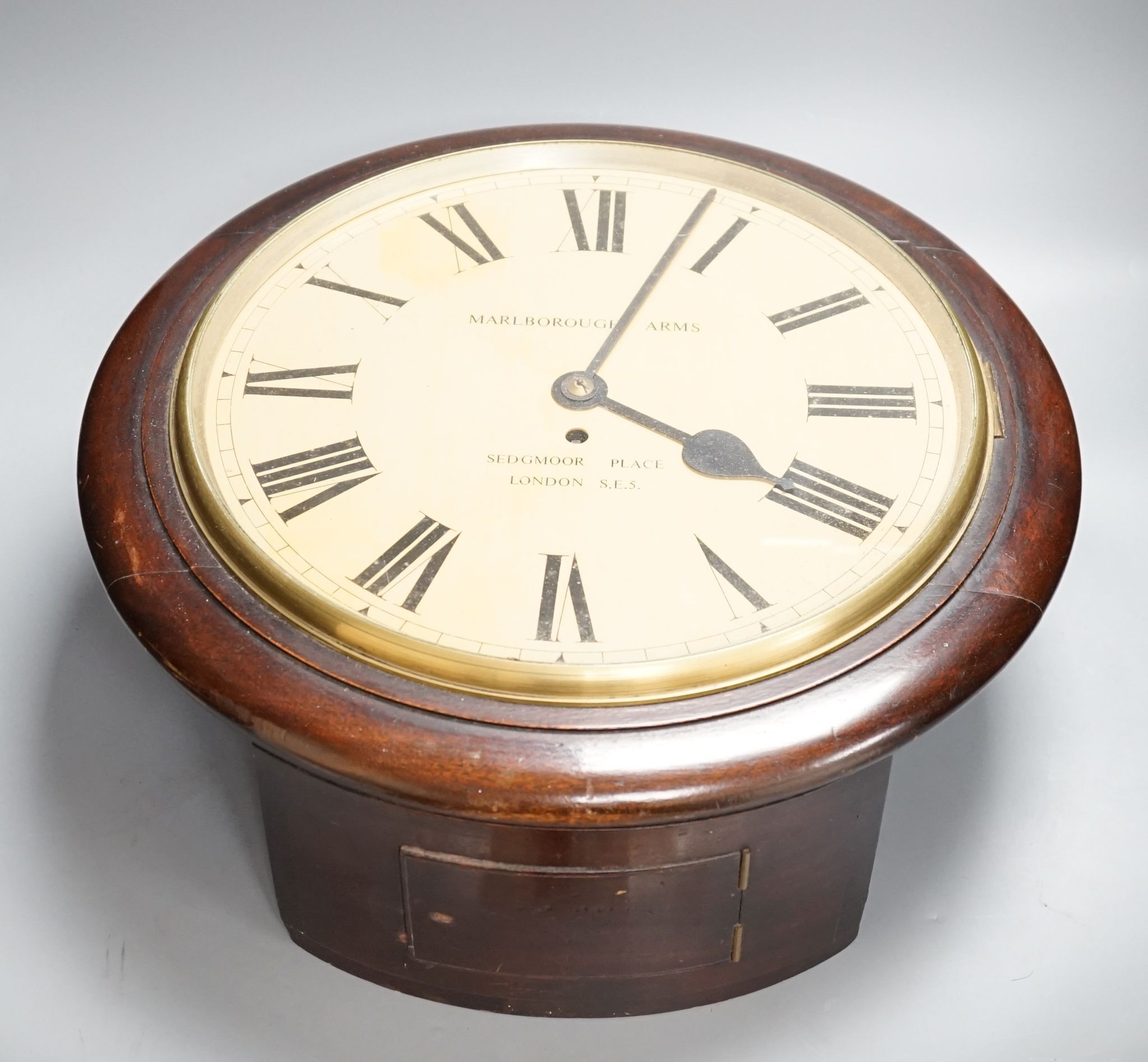 A mahogany dial clock, Marlborough Arms, Sedgmoor Place, London SE5., 48 cms diameter.